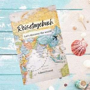 Reisetagebuch mit einer Weltkarte liegt auf einem blauen sandigen Tisch